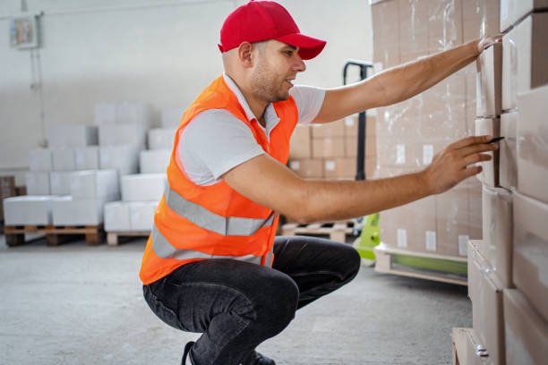 Male warehouse worker transferring boxes full of goods